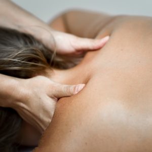 Young woman receiving a back massage in a spa center. Female patient is receiving treatment by professional therapist.